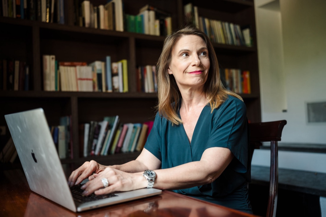 Sonja Kreye schreibt am Laptop vor einem Bücherregal